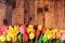 Easter rustic background. Pink and yellow tulips and daffodil flowers in the row on old wooden planks