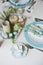 Easter and spring festive table decorated in blue and white tones in natural rustic style, with eggs, bunny, fresh flowers