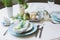 Easter and spring festive table decorated in blue and white tones in natural rustic style, with eggs, bunny, fresh flowers