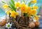 Easter still life with bouquet of daffodils in vase from bark of wood, Easter eggs and cute rabbit