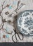 Easter still life. Vintage plate, fork, scissors, quail eggs, paper garland, branches on a grey table, top view.