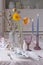 Easter table decoration: poppies and flowering aspen branches in vases, rabbit figurines, candles in crystal candlesticks.