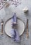Easter table setting with grey plate and violet decor on grey table. Top view. Vertical format