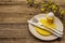 Easter table setting on old wooden background. Spring holiday card template. Cutlery, crochet napkin, egg, flowering sprigs of