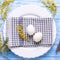 Easter table setting. White eggs, napkin on a plate, mimosa flowers, fork, knife on a blue wooden table Square