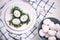 Easter table setting with white eggs in a nest, on a blue and white checkered napkin. Nearby are figures of rabbits. Copy space,