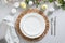 Easter table setting with yellow chick, eggs, fresh flowers on gray linen tablecloth.