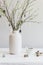 Easter tree and quail eggs on a white table. Birch tree branches decorated with white and gray painted eggs.