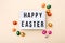 Easter wishes on lightbox with chocolate mini eggs wrapped in a colorful foil on a beige background, top view