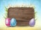 Easter wooden sign with painted 3d realistic eggs in green glass and flowers on yellow and blue bokeh backdrop.