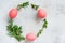 Easter wreath of pine needles, boxwood and painted eggs on light background.