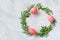 Easter wreath of pine needles, boxwood and painted eggs on light background.