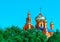 Eastern Church with gold domes or cupolas and orthodox crosses againts blue sky and green trees in Pokrov city park, Ukraine at su