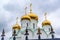 Eastern orthodox crosses on gold domes, cupolas, againts blue sky with clouds.