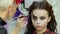 Easy Halloween Makeup. Girl in a beauty salon. Applying a stylistic pattern on the face of the model. The work of a master stylist