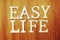 Easy Life word alphabet letters on wooden background