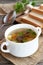 Easy mushroom soup with vegetables. Chopped bread on a kitchen cutting board, spoon, parsley, fresh champignons on a wooden table