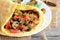 Easy mushrooms omelet recipe. Homemade omelette stuffed with mushrooms, tomatoes and dill on a plate and old wooden background