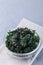 Easy three ingredient baked green kale chips with sea salt and olive oil, in glass bowl, vertical, copy space
