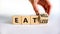 Eat well or eat less symbol. Businessman turns a cube and changes words `eat less` to `eat well`. Beautiful white background.