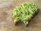 Eaten sandwich with guacamole lying on a wooden cut board