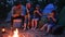 Eating dinner in evening near flames on nature, family enjoying corn with salt, picnic on outdoors, travel camp