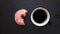 Eating pink donut and drinking a cup of coffee on dark background view from above, stop motion animation