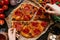 Eating pizza, top view. Hands taking slices of hot delicious pizza. Pizza ingredients on the wooden table