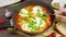 Eating shakshuka, tomato eggs. hands cutting poached eggs in tomatoes with fork, spicy shakshouka, slow motion 4k video