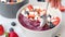 Eating with spoon berry smoothie bowl with granola, strawberries, blueberries and coconut.