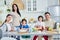 Eating together. Smiling hispanic parents spending time with their little children, having breakfast together at home