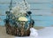 Eatser image includes a green, wire basket with colorful spotted eggs and baby`s breath on a rustic wooden background.