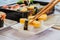 Eatting tamagoyaki sushi or sweet egg on rice and seaweed wrap on square white plate with chopsticks. Delicious japanese food