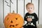 eautiful little girl with Down syndrome sitting near a pumpkin on Halloween dressed as a skeleton