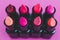 Eauty industry still-life with group of colorful lipsticks lined up on pink background shot from 45 degrees angle