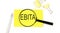 EBITA text on the sticker through magnifier. View from above. Business concept