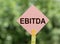 EBITDA - Earnings Before Interest, Taxes, Depreciation and Amortization - on a pink road sign on blurred green beckground