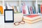 Ebook reader and reading glasses on bookshelf background.Copy space on digital tablet display