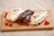 Eclair cakes with white and brown cream on wooden board