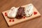 Eclair cakes with white and brown cream on wooden board