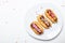 Eclairs cakes with chocolate icing and colorful sugar powder, white background, top view