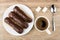 Eclairs with chocolate in plate, coffee in cup, lumpy sugar