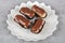 Eclairs with chocolate topping on serving plate. Traditional french eclairs with chocolate. Mini vanilla eclairs with chocolate