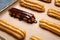 Eclairs with chocolate and whipped cream preparing on baking sheet