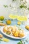Eclairs with lemon curd topping on serving plate with glass of limoncello on a light background, concept of Italian and French