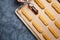 Eclairs, profiterole preparing on baking sheet, spreading chocolate with spoon