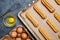 Eclairs or profiterole preparing with eggs on baking sheet background