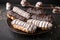 Eclairs or profiteroles with black chocolate and white chocolate with custard inside on a metal plate on a dark background.