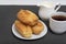 Eclairs and tea with milk. Traditional French eclairs. Profiteroles on white saucer