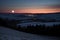 an eclipsed moon over a dark, moonlit landscape